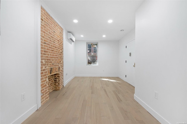 unfurnished living room with a wall unit AC, a fireplace, light hardwood / wood-style floors, and brick wall