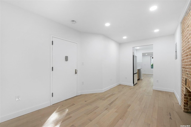 entrance foyer featuring light hardwood / wood-style floors, brick wall, and a brick fireplace