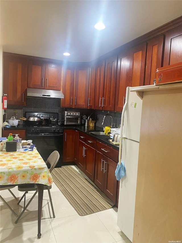 kitchen featuring black gas stove, backsplash, white fridge, and light tile patterned floors