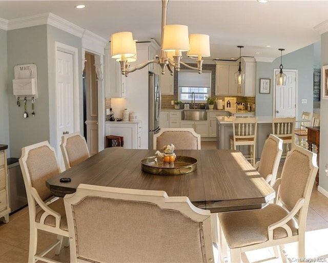 dining space featuring a notable chandelier, light tile patterned floors, sink, and ornamental molding