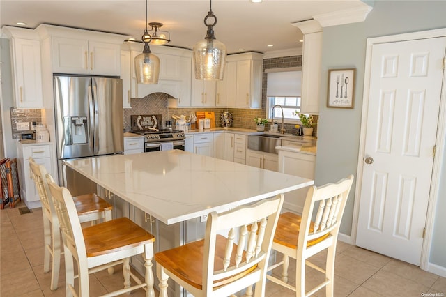 kitchen with sink, stainless steel appliances, crown molding, pendant lighting, and a kitchen island