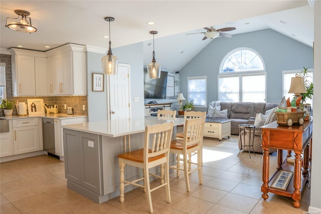 kitchen with ceiling fan, dishwasher, a kitchen breakfast bar, backsplash, and white cabinets