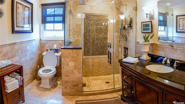 bathroom featuring vanity, tile patterned flooring, toilet, tile walls, and a shower with shower door