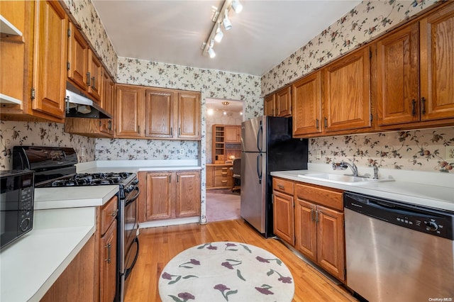 kitchen featuring sink, light hardwood / wood-style floors, track lighting, and black appliances