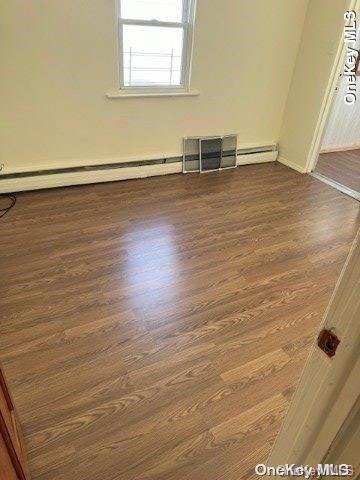 spare room featuring a baseboard radiator and dark hardwood / wood-style floors