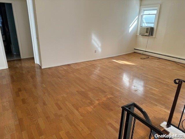 spare room with hardwood / wood-style flooring and a baseboard heating unit