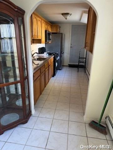 kitchen with black range oven, light tile patterned floors, sink, and a baseboard heating unit