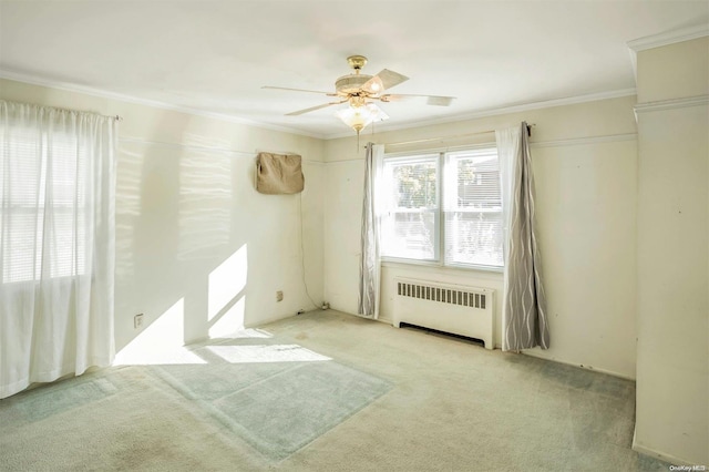 carpeted empty room featuring ceiling fan, radiator heating unit, and crown molding