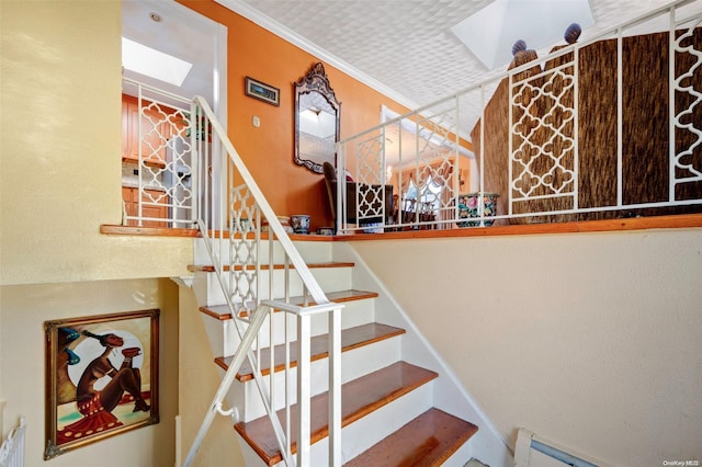 staircase featuring ornamental molding, baseboard heating, and a skylight