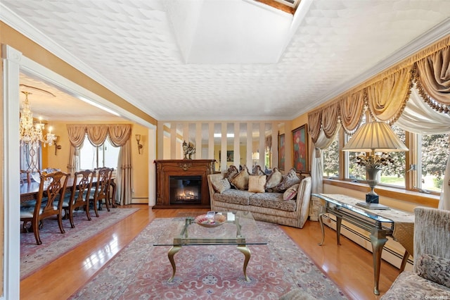 living room with light hardwood / wood-style floors, crown molding, a wealth of natural light, and a baseboard heating unit