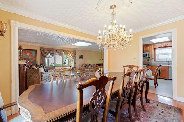 dining room with light hardwood / wood-style floors, sink, crown molding, and a chandelier