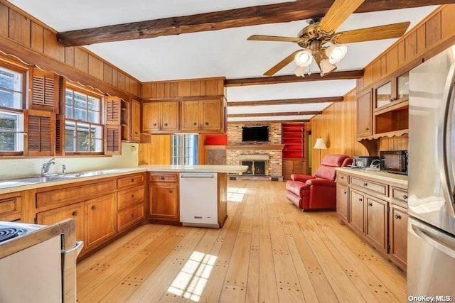 kitchen with beam ceiling, light wood-type flooring, a brick fireplace, and wooden walls