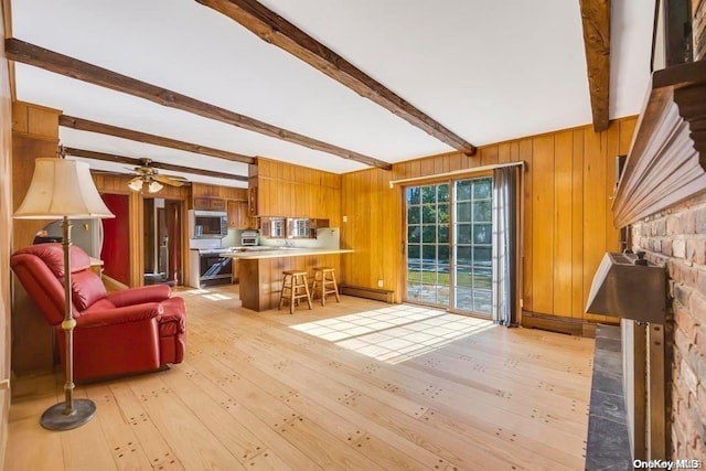 living room featuring beamed ceiling, ceiling fan, light hardwood / wood-style floors, and wood walls