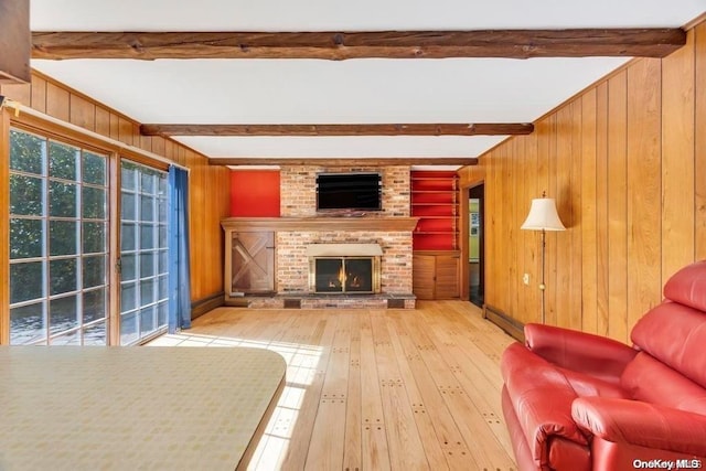 unfurnished living room with beam ceiling, hardwood / wood-style flooring, a brick fireplace, and wooden walls