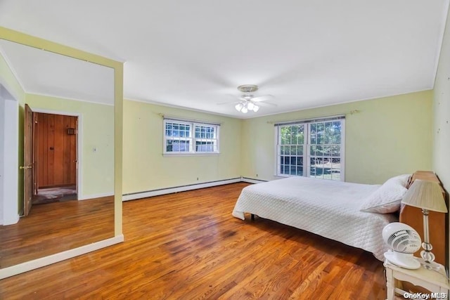 bedroom featuring ceiling fan, wood-type flooring, and a baseboard heating unit