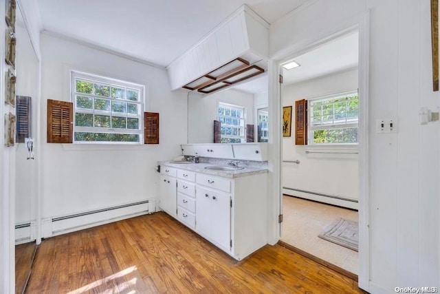 kitchen with white cabinets, light hardwood / wood-style flooring, a baseboard heating unit, and sink