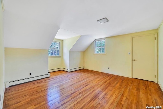 bonus room with a baseboard heating unit, light wood-type flooring, and lofted ceiling