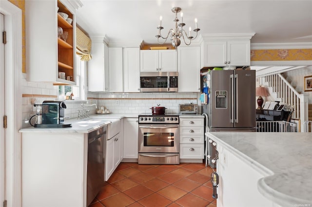 kitchen featuring light stone countertops, appliances with stainless steel finishes, tasteful backsplash, white cabinets, and a chandelier