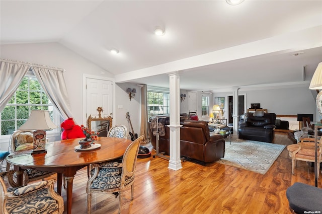 dining room featuring decorative columns, wood-type flooring, and lofted ceiling