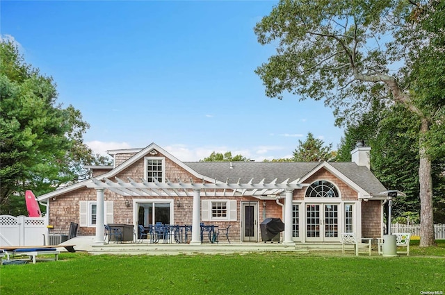 back of property with a pergola, french doors, a lawn, and fence
