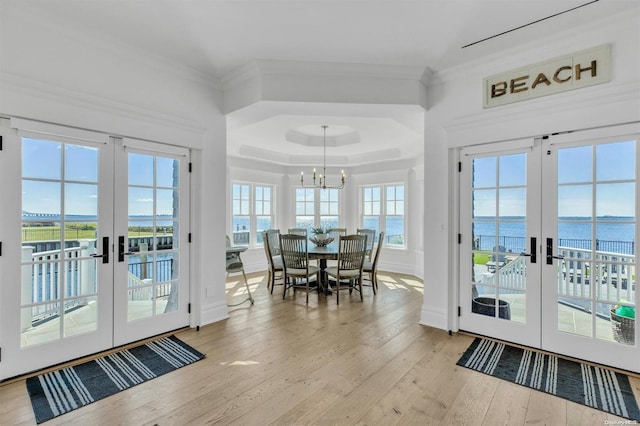 doorway featuring french doors, light wood-type flooring, a water view, and ornamental molding