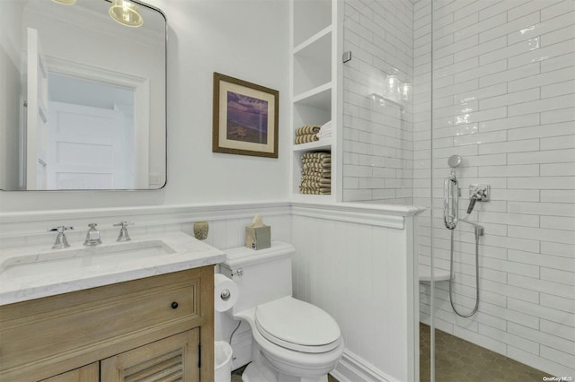 bathroom featuring a tile shower, vanity, and toilet