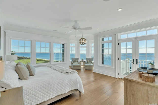 bedroom featuring french doors, crown molding, light hardwood / wood-style floors, access to outside, and a water view