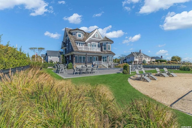 rear view of property featuring a patio, a balcony, and a lawn