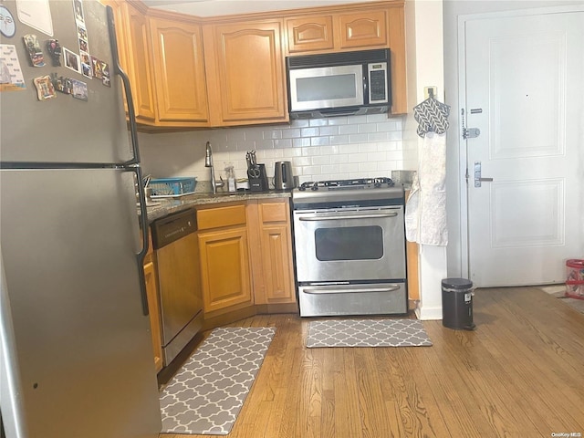 kitchen featuring decorative backsplash, appliances with stainless steel finishes, sink, and hardwood / wood-style floors