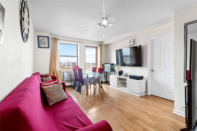 living room featuring ceiling fan, a baseboard heating unit, and light wood-type flooring