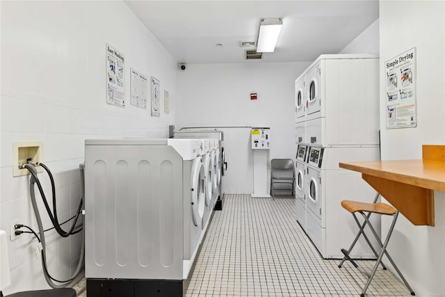 clothes washing area featuring stacked washer and clothes dryer, washer and clothes dryer, and tile walls