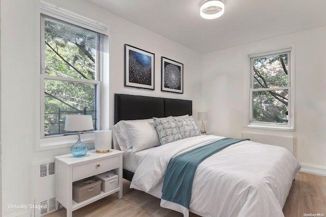 bedroom with light hardwood / wood-style flooring and radiator heating unit