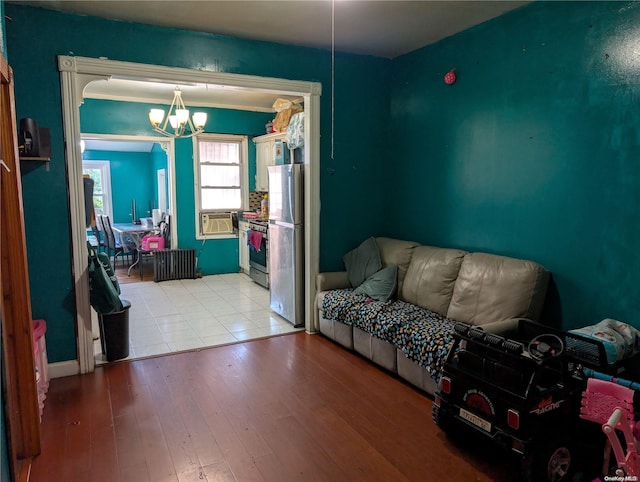 living room featuring cooling unit, an inviting chandelier, crown molding, and light hardwood / wood-style flooring