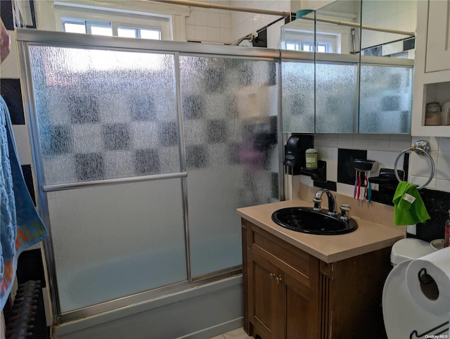 bathroom with shower / bath combination with glass door, vanity, and backsplash