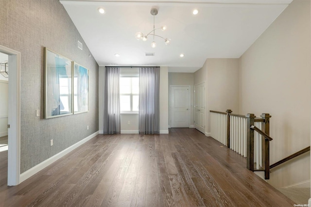 unfurnished room featuring vaulted ceiling, dark wood-type flooring, and a chandelier