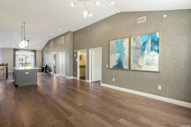 unfurnished living room with dark hardwood / wood-style flooring, high vaulted ceiling, and an inviting chandelier