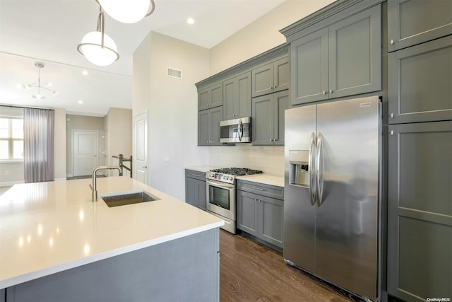 kitchen with decorative backsplash, appliances with stainless steel finishes, sink, pendant lighting, and dark hardwood / wood-style floors