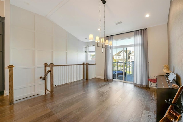 unfurnished room featuring wood-type flooring, vaulted ceiling, and an inviting chandelier