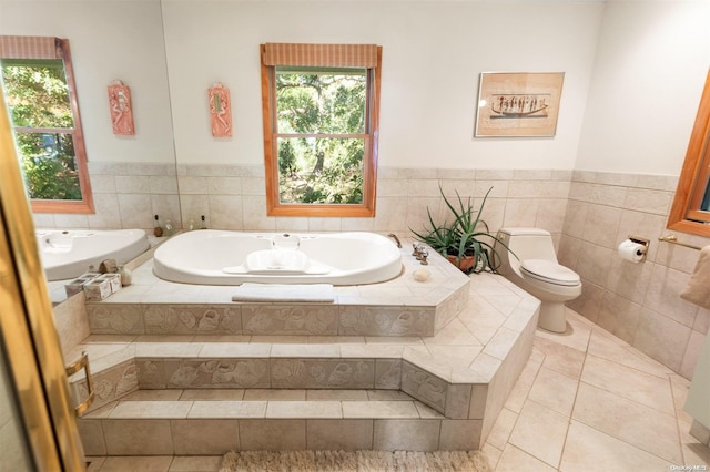 bathroom with tile patterned flooring, a relaxing tiled tub, and toilet