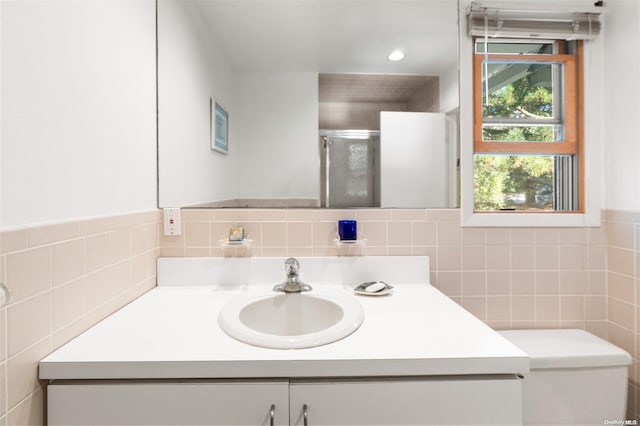 bathroom with tile walls, vanity, an enclosed shower, and toilet