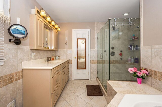 bathroom featuring tile patterned flooring, vanity, tile walls, and a shower with shower door