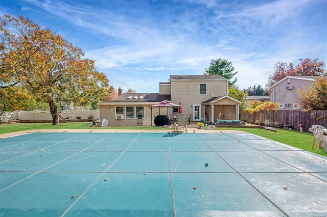 rear view of house featuring a lawn, a patio, and a covered pool