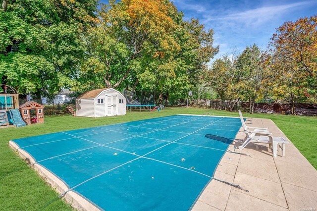 view of pool with a yard, a trampoline, a playground, a storage shed, and a patio area