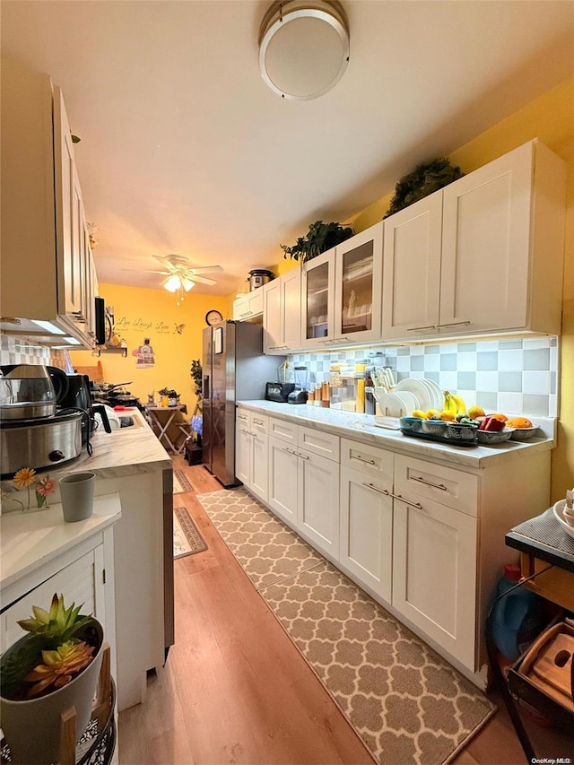 kitchen featuring white cabinets, backsplash, and light hardwood / wood-style flooring