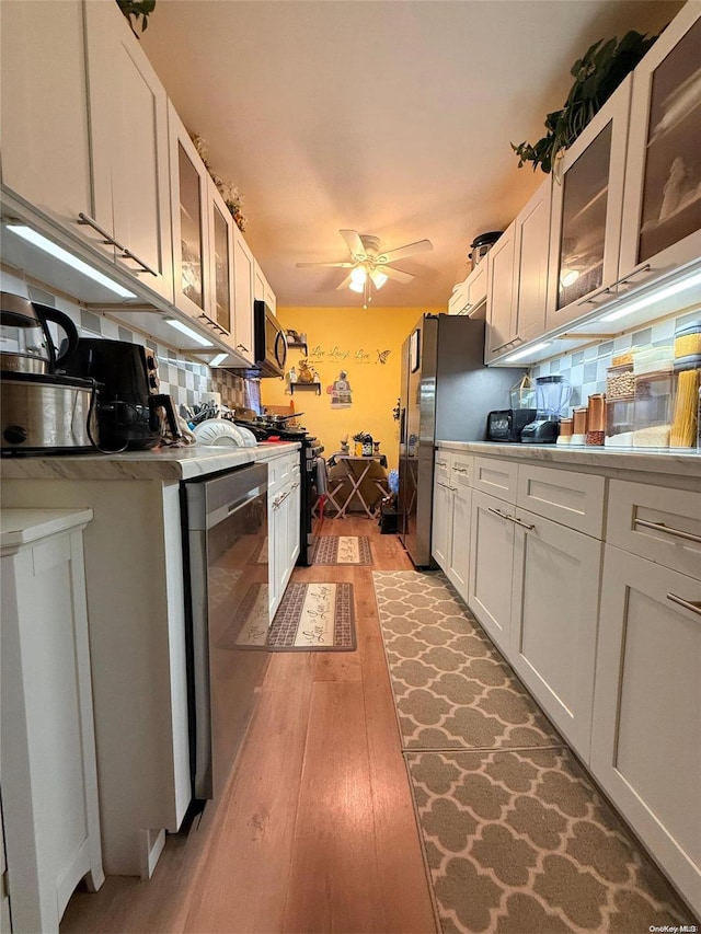 kitchen with white cabinets, decorative backsplash, and stainless steel appliances