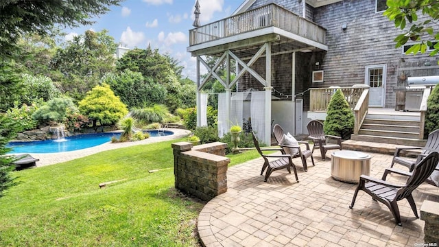 view of patio with a balcony, a swimming pool side deck, pool water feature, and an outdoor fire pit