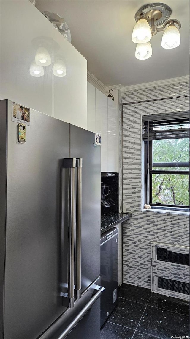 kitchen with dark stone countertops, crown molding, white cabinets, tile walls, and appliances with stainless steel finishes