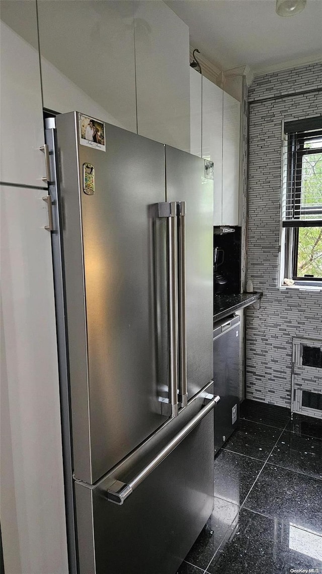 kitchen featuring white cabinets, stainless steel appliances, and tile walls