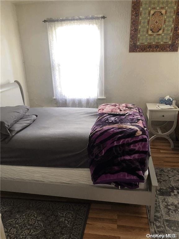 bedroom with multiple windows and hardwood / wood-style flooring