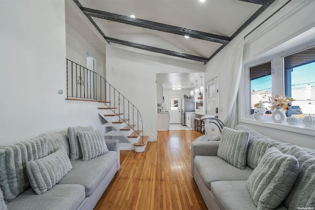 living room featuring beamed ceiling, light wood-type flooring, and high vaulted ceiling